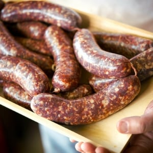 Holding a tray of loukaniko sausage.