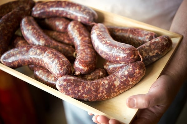 Holding a tray of loukaniko sausage