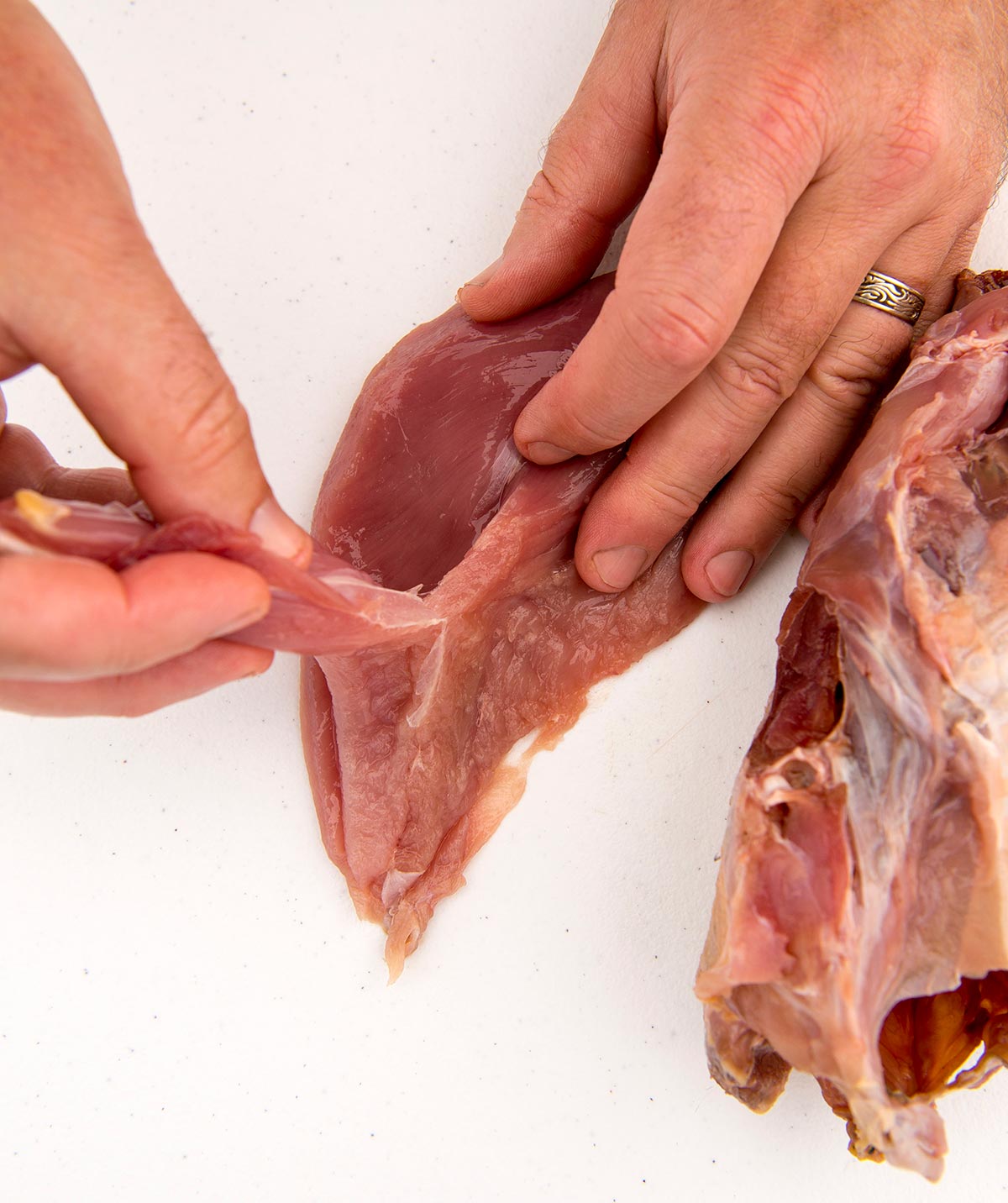 Removing the tender from the breast meat. 