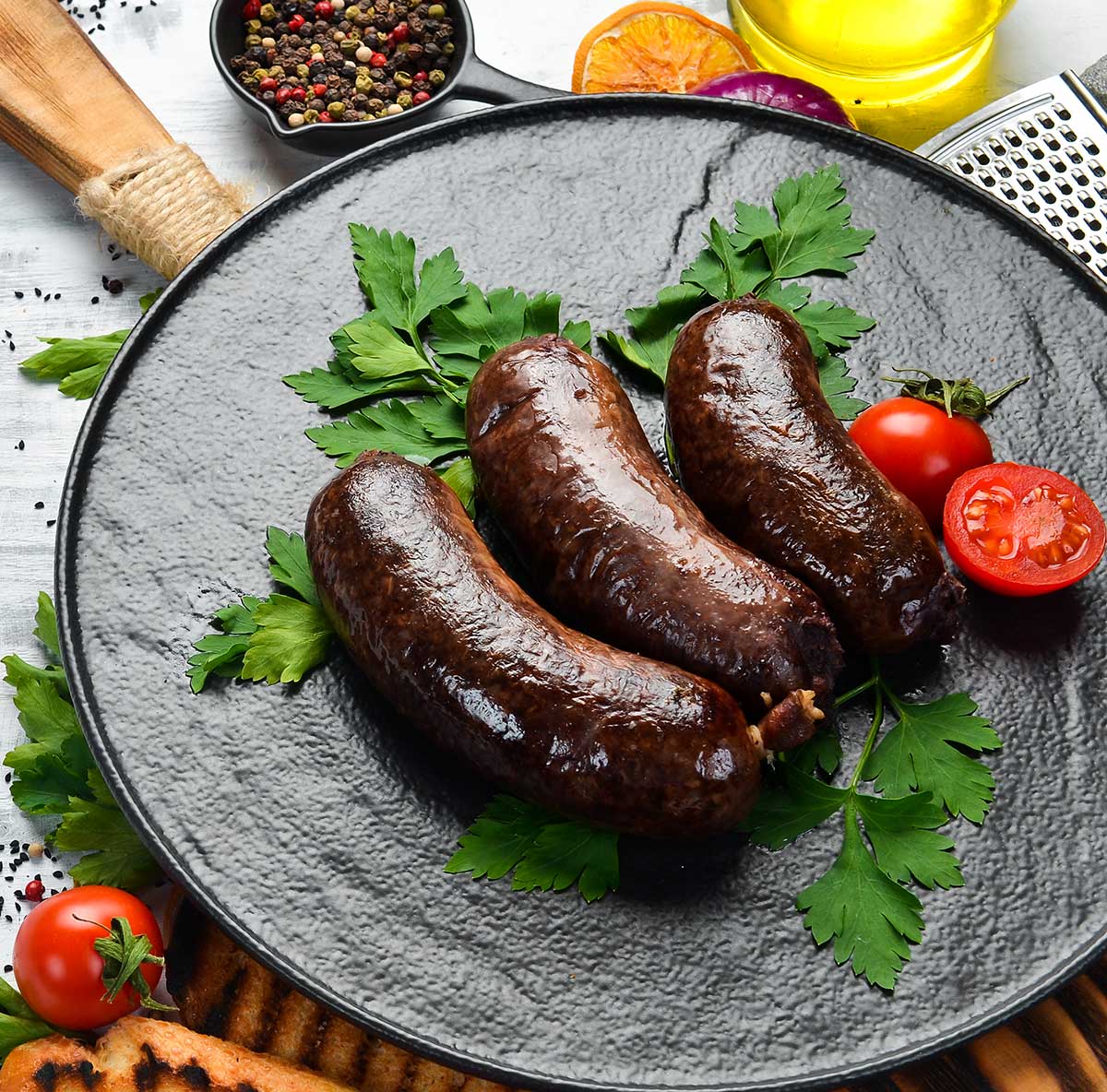 Finished blood sausage recipe on a plate with tomatoes and parsley. 