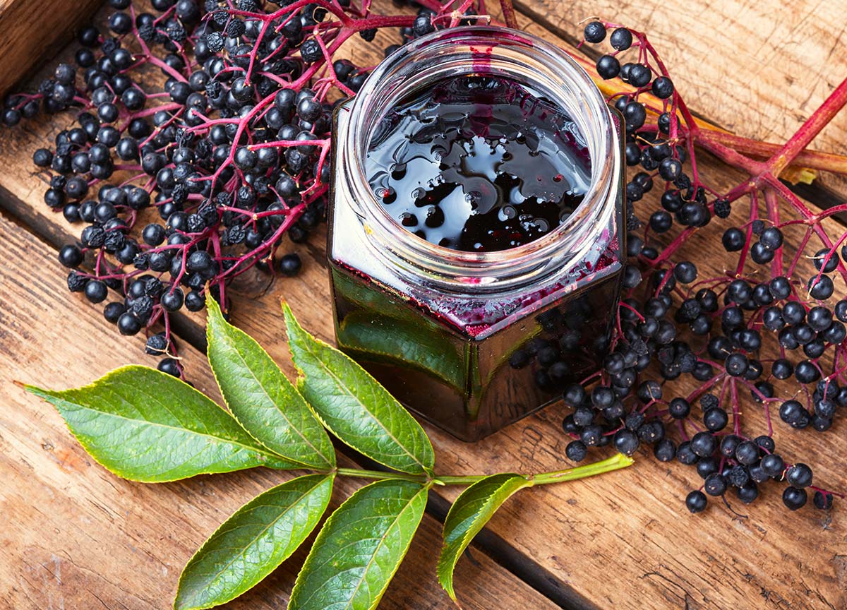 Elderberries, leaves and a jar of elderberry jam. 
