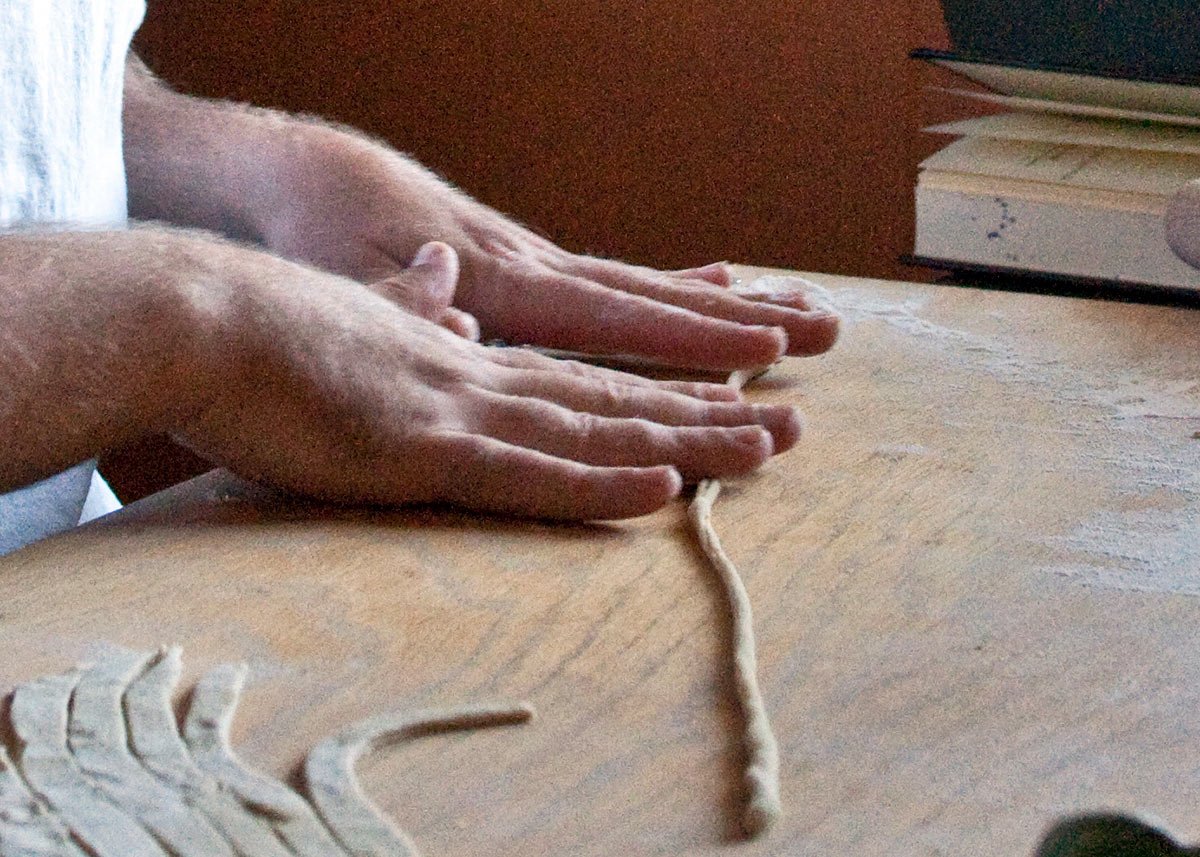 Close up of rolling pici pasta. 