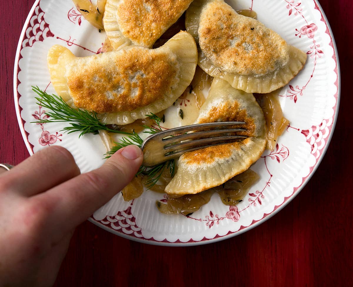 Cutting a mushroom pierogi with a fork.