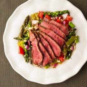 Grilled venison steak with a summer salad on a plate.