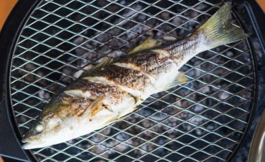 A grilled whole fish over the coals.