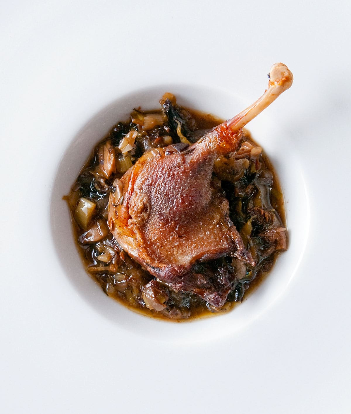 Braised duck legs over a bed of mushrooms and leeks. 