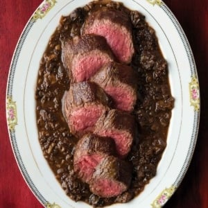 Morel sauce with venison loin on a platter.