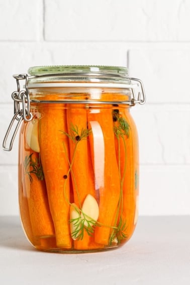 Fermented carrots in a jar on the counter.