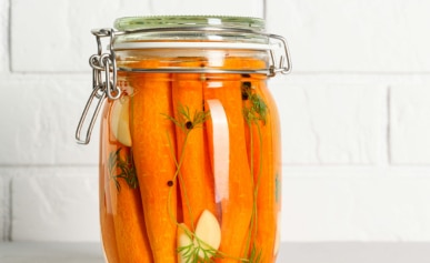 Fermented carrots in a jar on the counter.