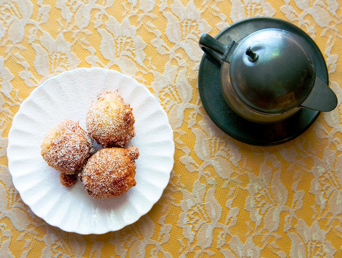 A plate of elderflower fritters with a teapot. 