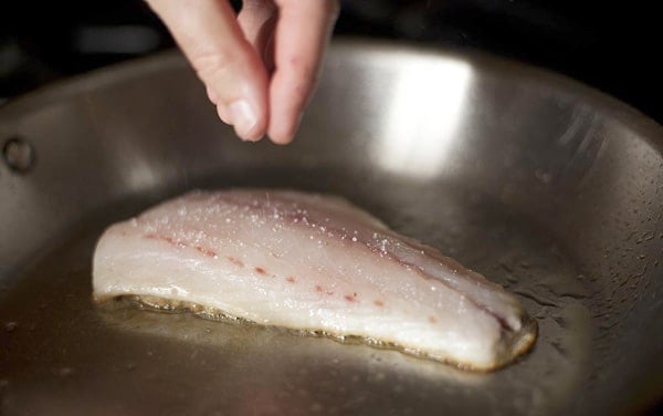 Salting the meat side of a fish while searing. 