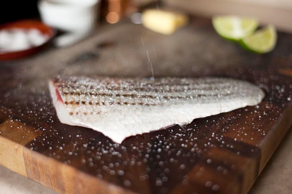 Salting a fillet of striped bass. 