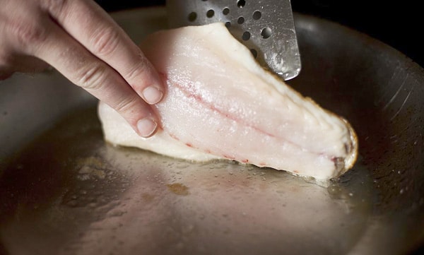 carefully flipping a fish while searing