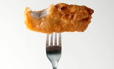 Fish and chips on a fork with a bite taken out