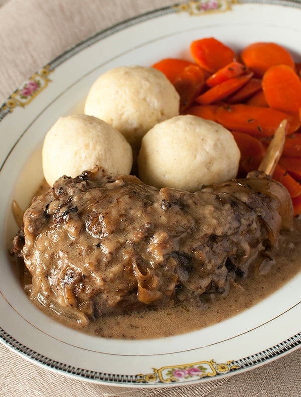 A plate of hasenpfeffer with semolina dumplings and glazed carrots. 