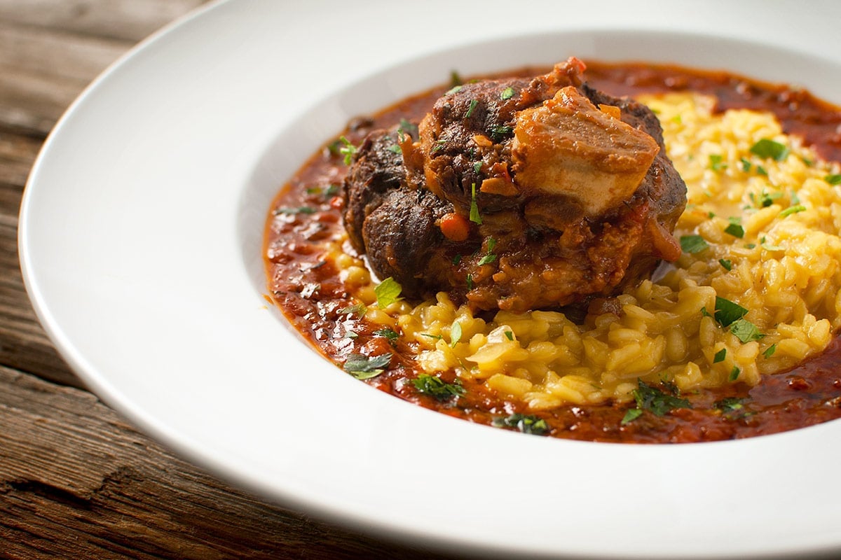 Elk osso buco as ossobuco milanese in a bowl with risotto. 