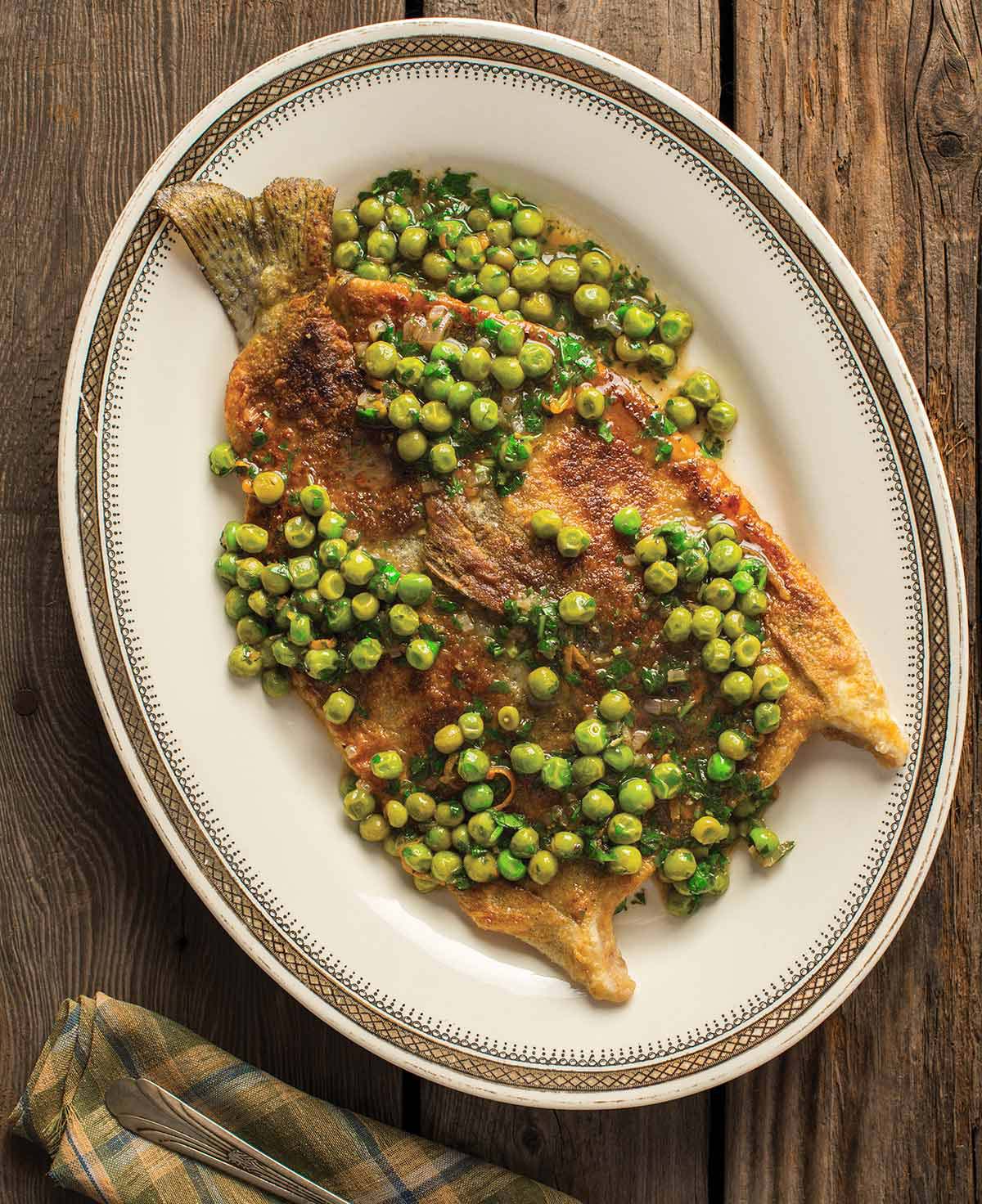 Butterflied trout with peas and parsley on a plate. 