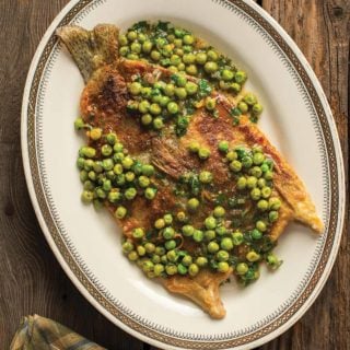 A plate of pan fried trout with peas