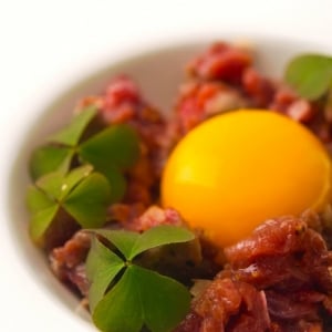 A bowl of venison tartare with an egg yolk.