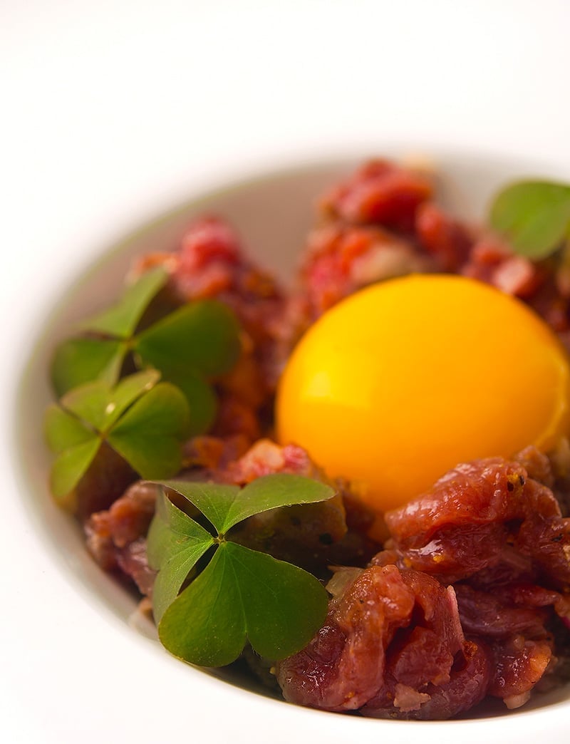 A bowl of venison tartare with an egg yolk.