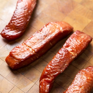 pieces of candied salmon on a cutting board.