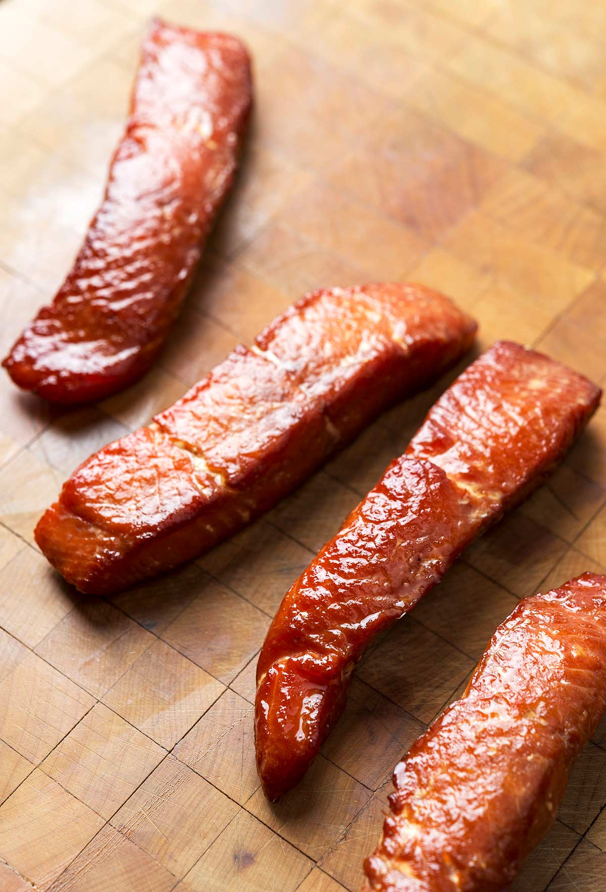 pieces of candied salmon on a cutting board. 
