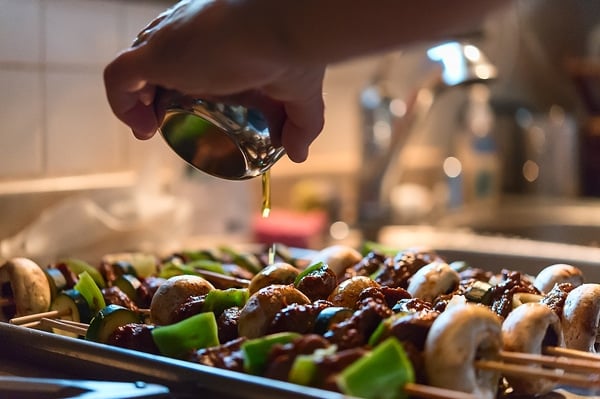 Pouring olive oil on venison kebabs before grilling