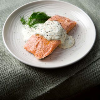 Butter poached salmon with dill sauce on a plate