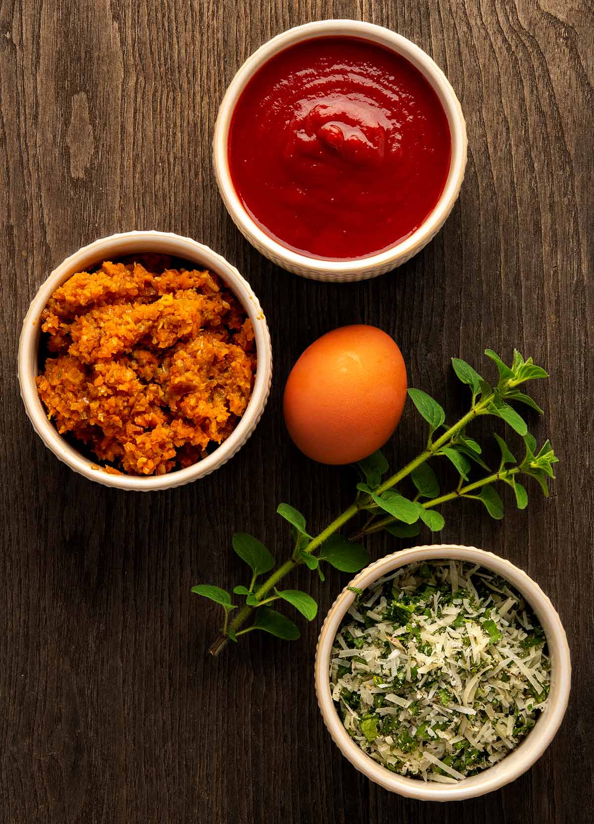 Some ingredients for venison meatloaf: eggs, herbs, cheese, tomato sauce and onions. 