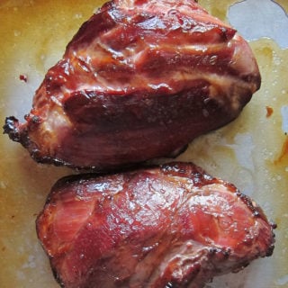Two small honey glazed smoked hams on a baking sheet.