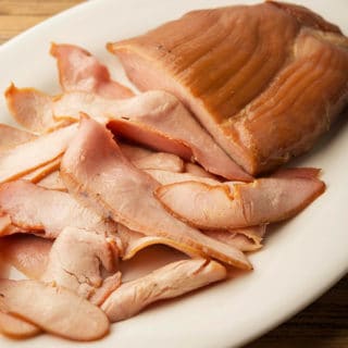 Smoked wild turkey breast, sliced on a plate.