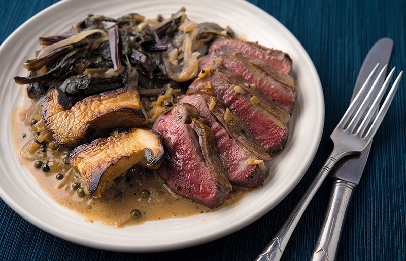 Steak au poivre, served with mushrooms and greens