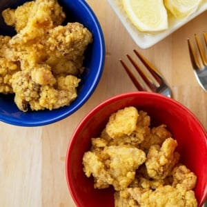 Close up of fried clams in small bowls with lemon slices.