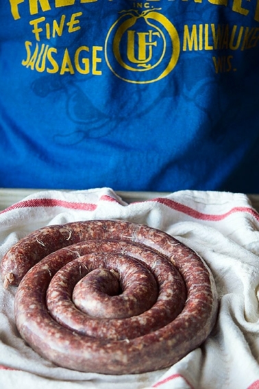 Holding a tray of boerewors sausages.