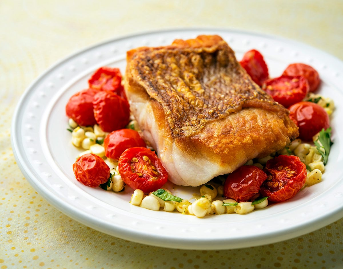 A plate of pan seared red snapper with cherry tomatoes.