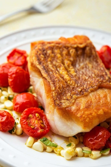 pan seared red snapper on a plate with roasted cherry tomatoes.