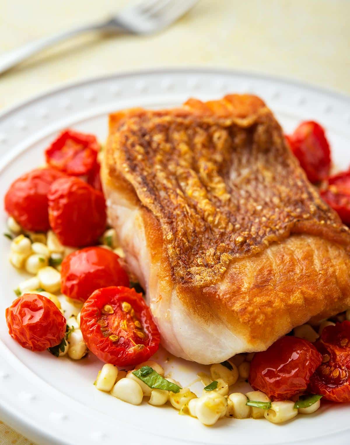 pan seared red snapper on a plate with roasted cherry tomatoes. 