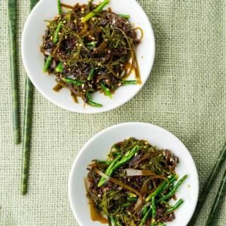 Two plates of Japanese seaweed salad with chopsticks.