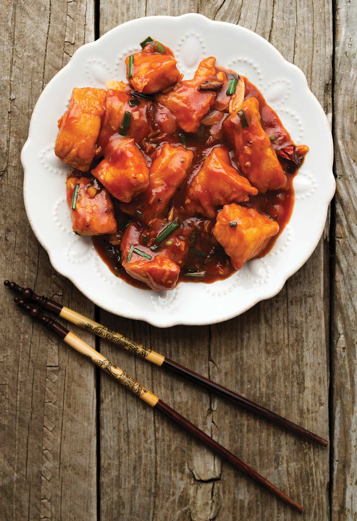 A plate of sweet and sour fish with chopsticks