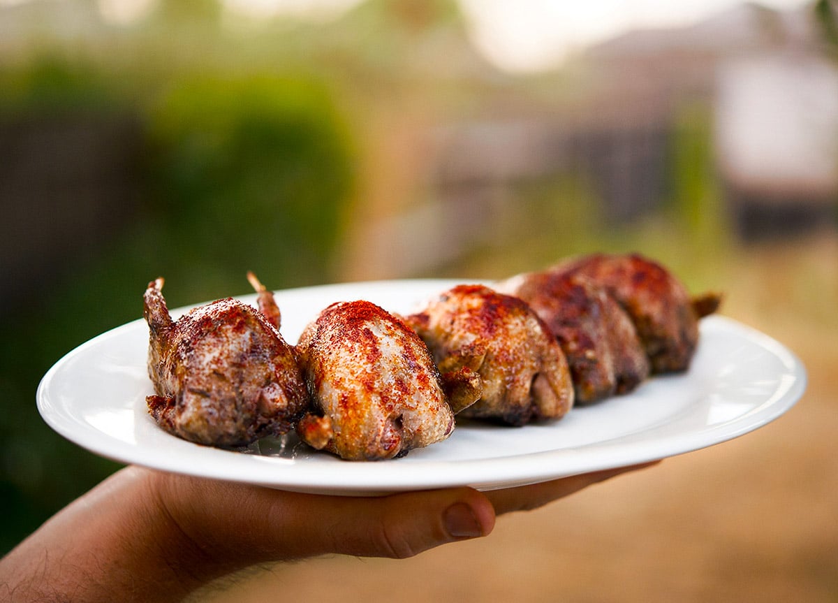 Holding a platter of the finished dove recipe, grilled doves. 