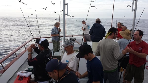 Lots of people fishing on a boat. 