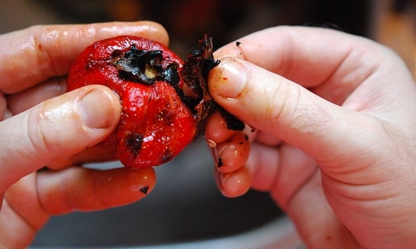 Peeling charred skin from a roasted red pepper