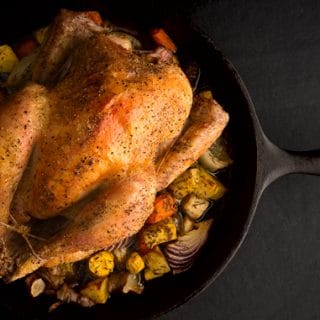 A beautiful roast chicken on a cast iron frying pan.