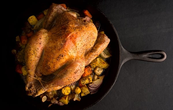 A beautiful roast chicken on a cast iron frying pan. 