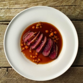 Beer sauce with duck and currants on a plate.