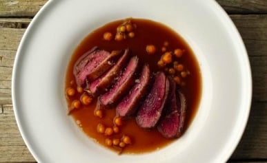 Beer sauce with duck and currants on a plate.