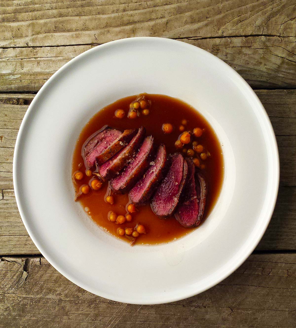 Beer sauce with duck and currants on a plate. 