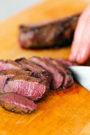 Finished duck breasts recipe on a cutting board.