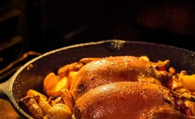 Slow roast duck in a cast iron pan with root vegetables.