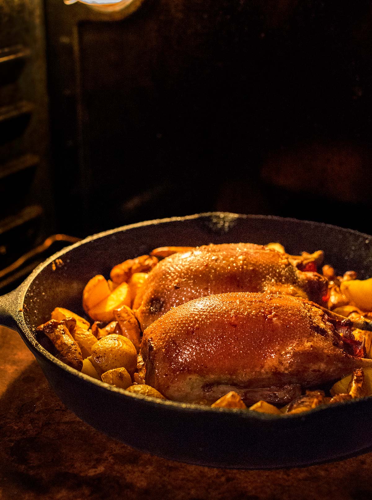 Slow roast duck in a cast iron pan with root vegetables.